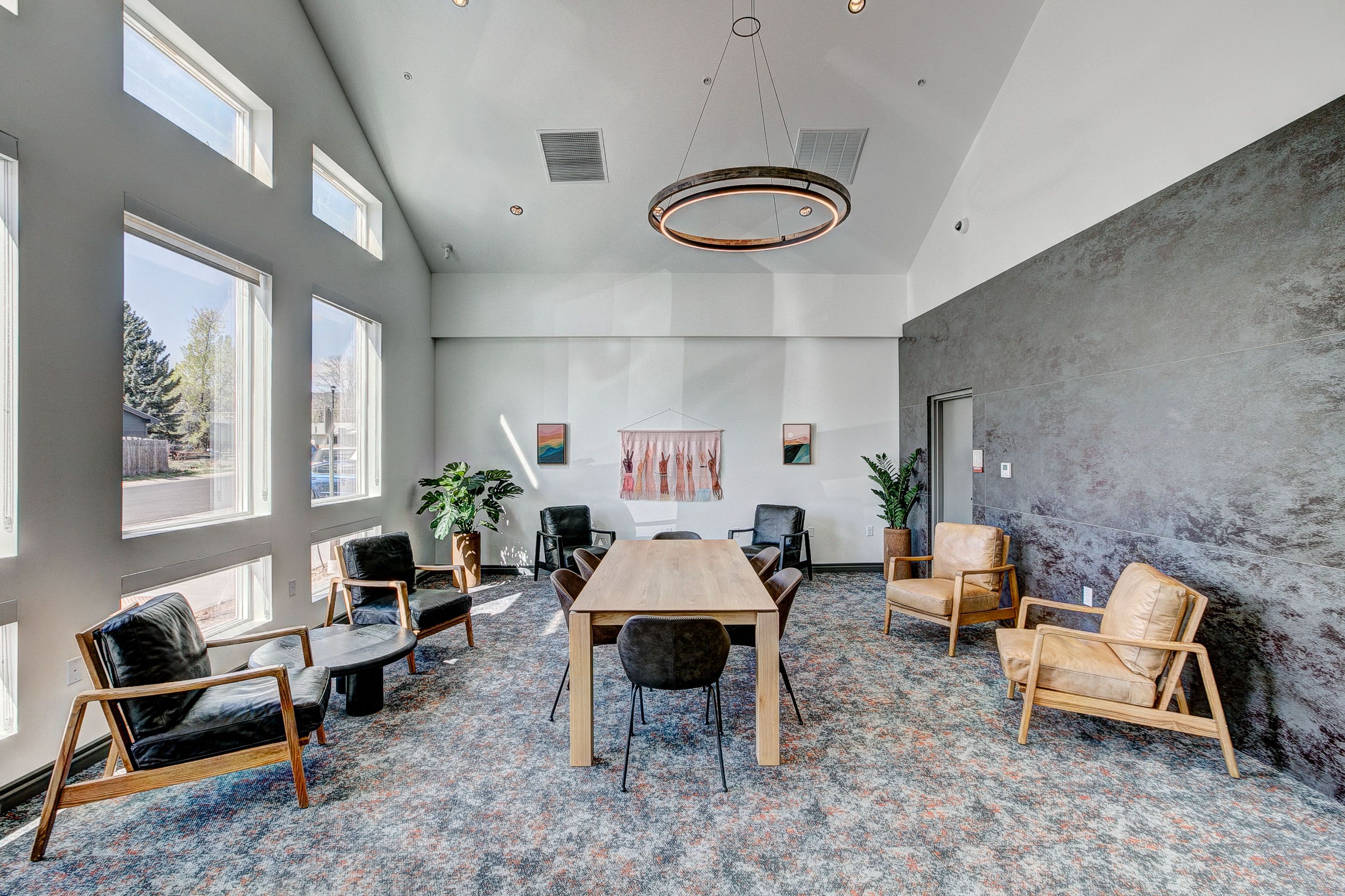 A room with a grey wall and a wooden table with chairs.