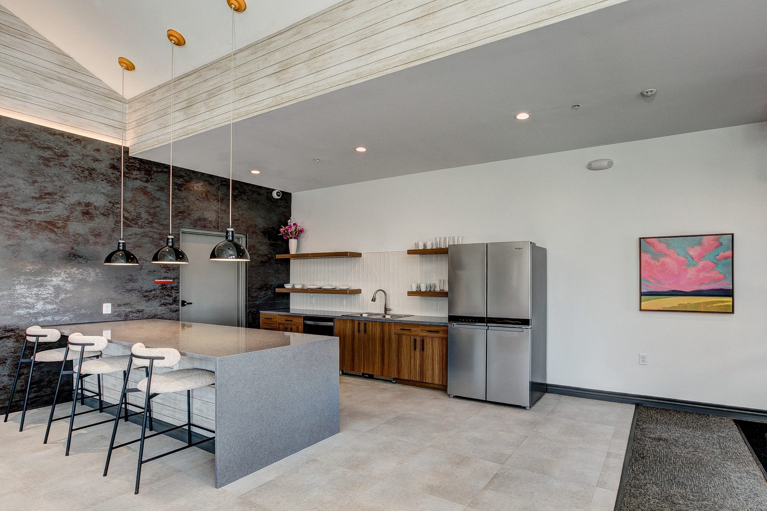 A kitchen with a grey island and stools.