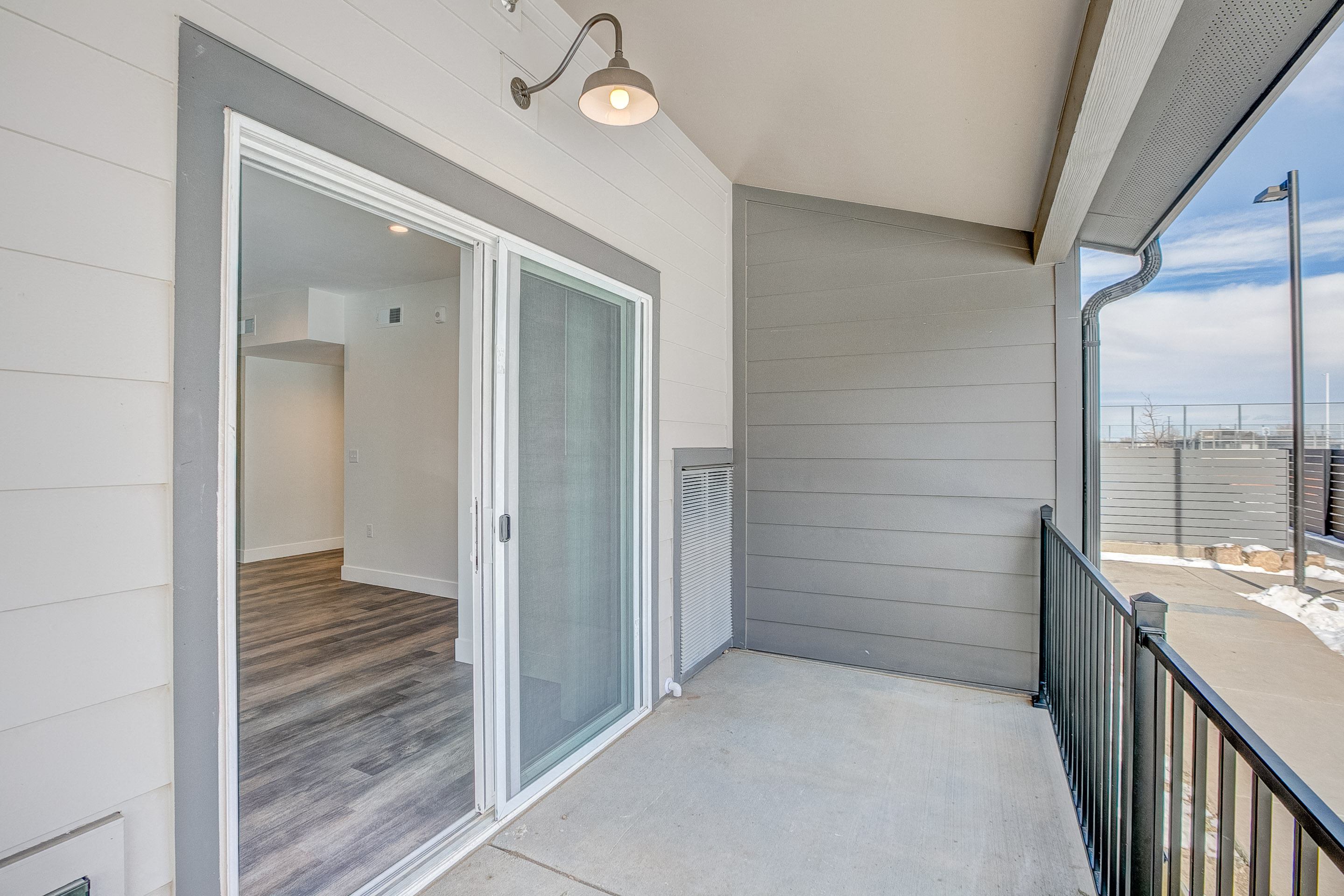 A balcony with a glass door leading to a room.