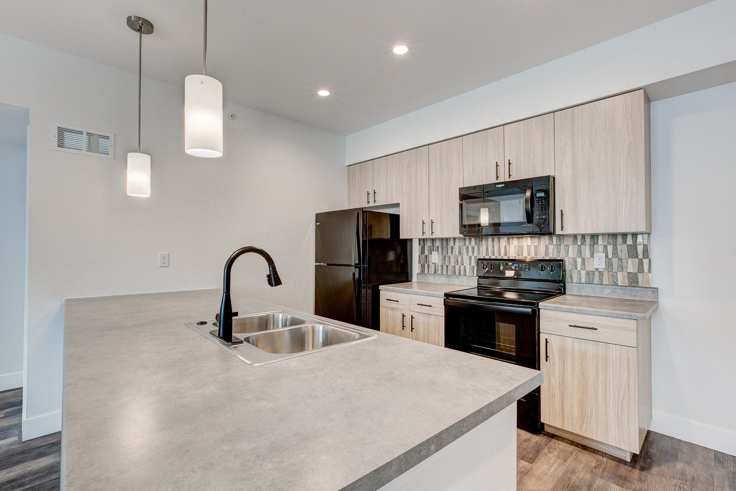 A kitchen with a sink, stove, and cabinets.