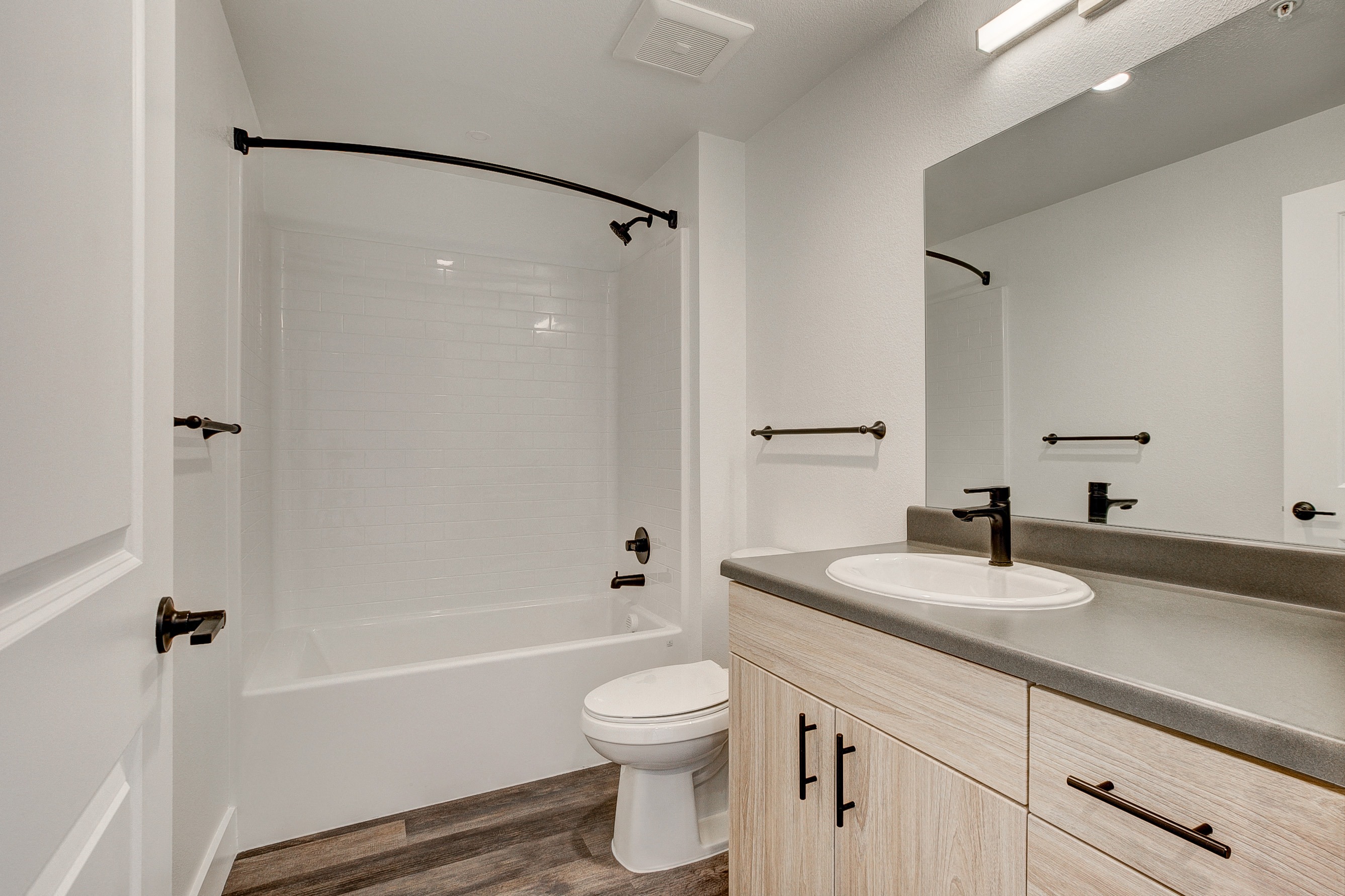 A white bathroom with a toilet, sink, and mirror.
