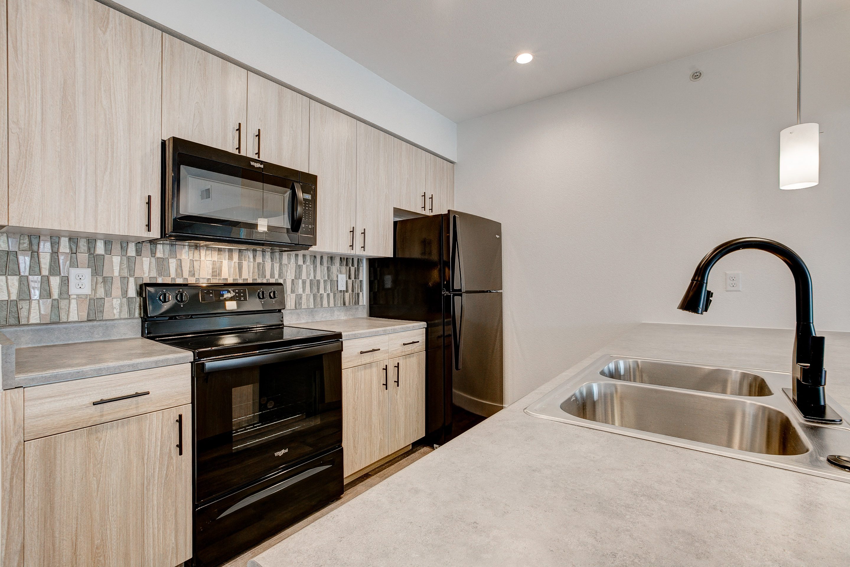 A modern kitchen with a stainless steel sink and dark wood cabinets.