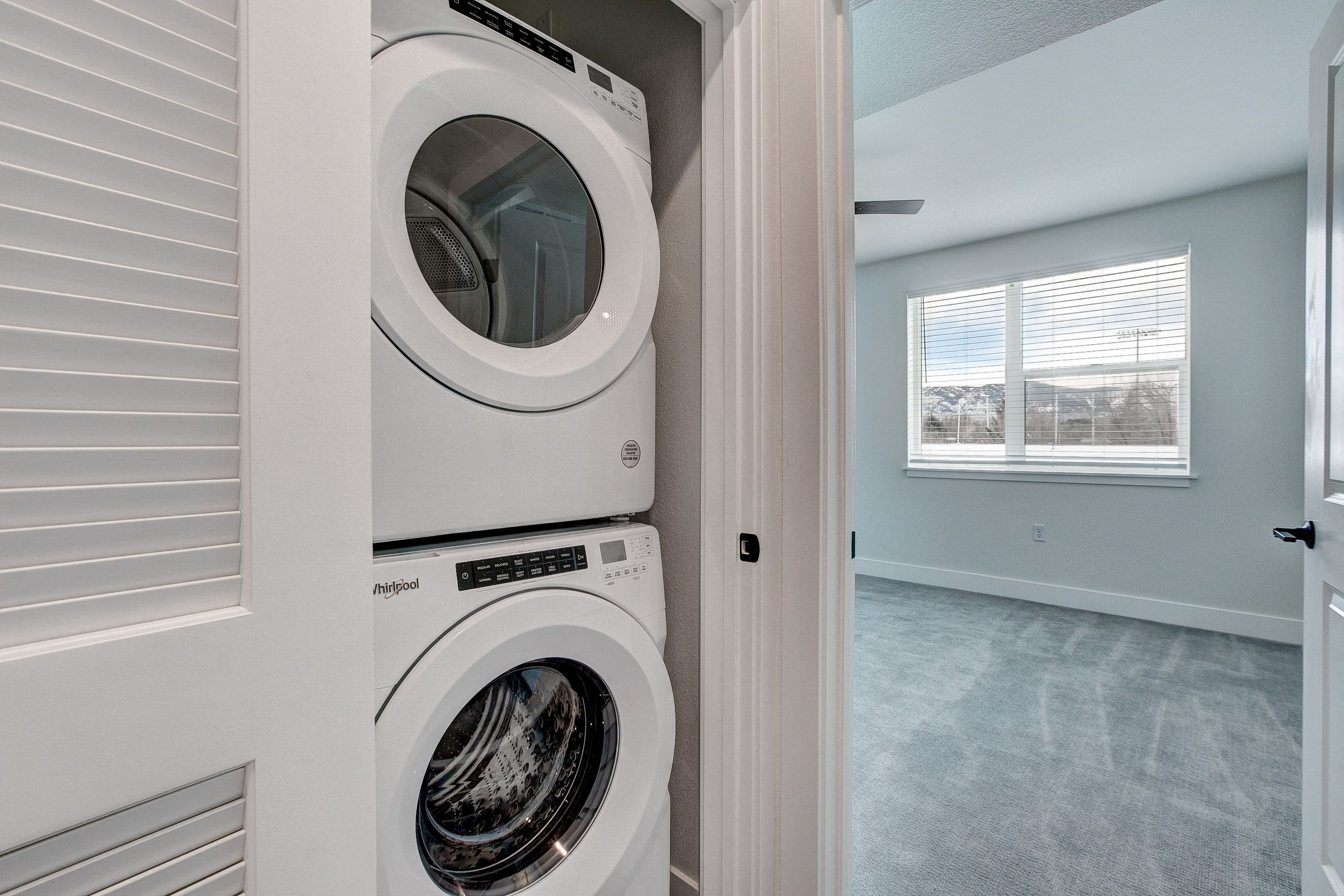 A white washing machine and dryer stacked on top of each other in a laundry room.