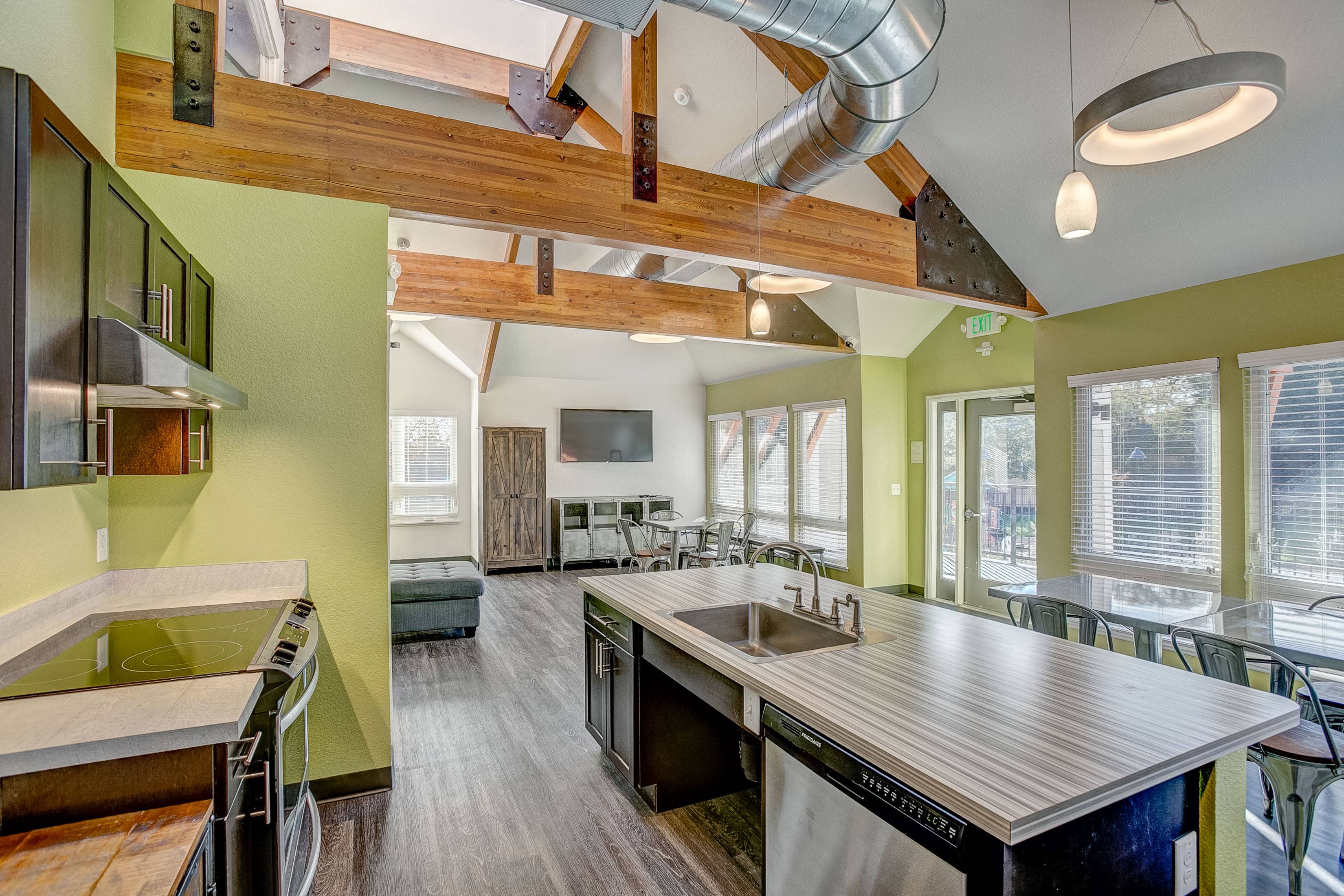 A kitchen with a wooden ceiling beam and a stainless steel island.