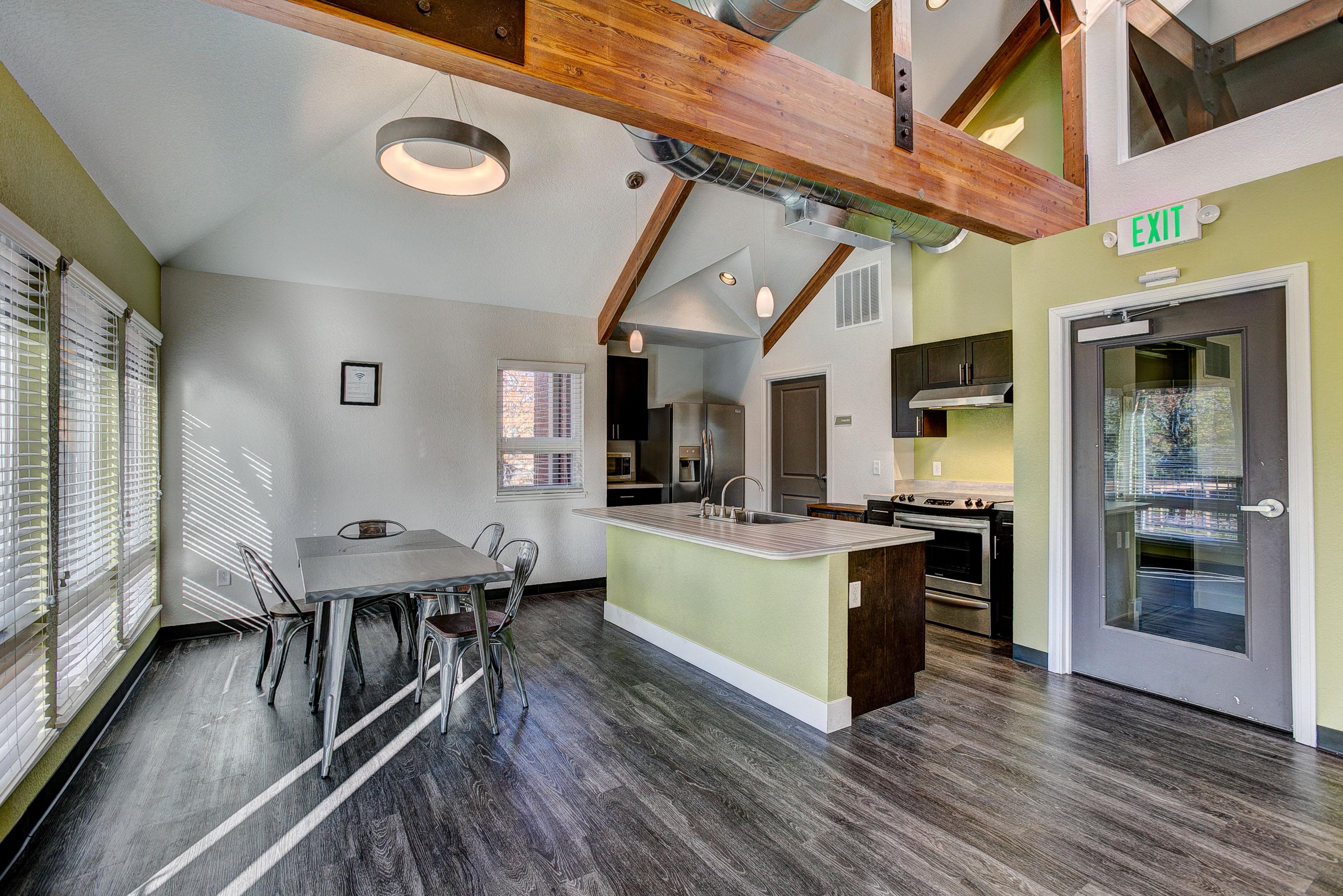 A kitchen with a table and chairs in the foreground and a green wall in the background.