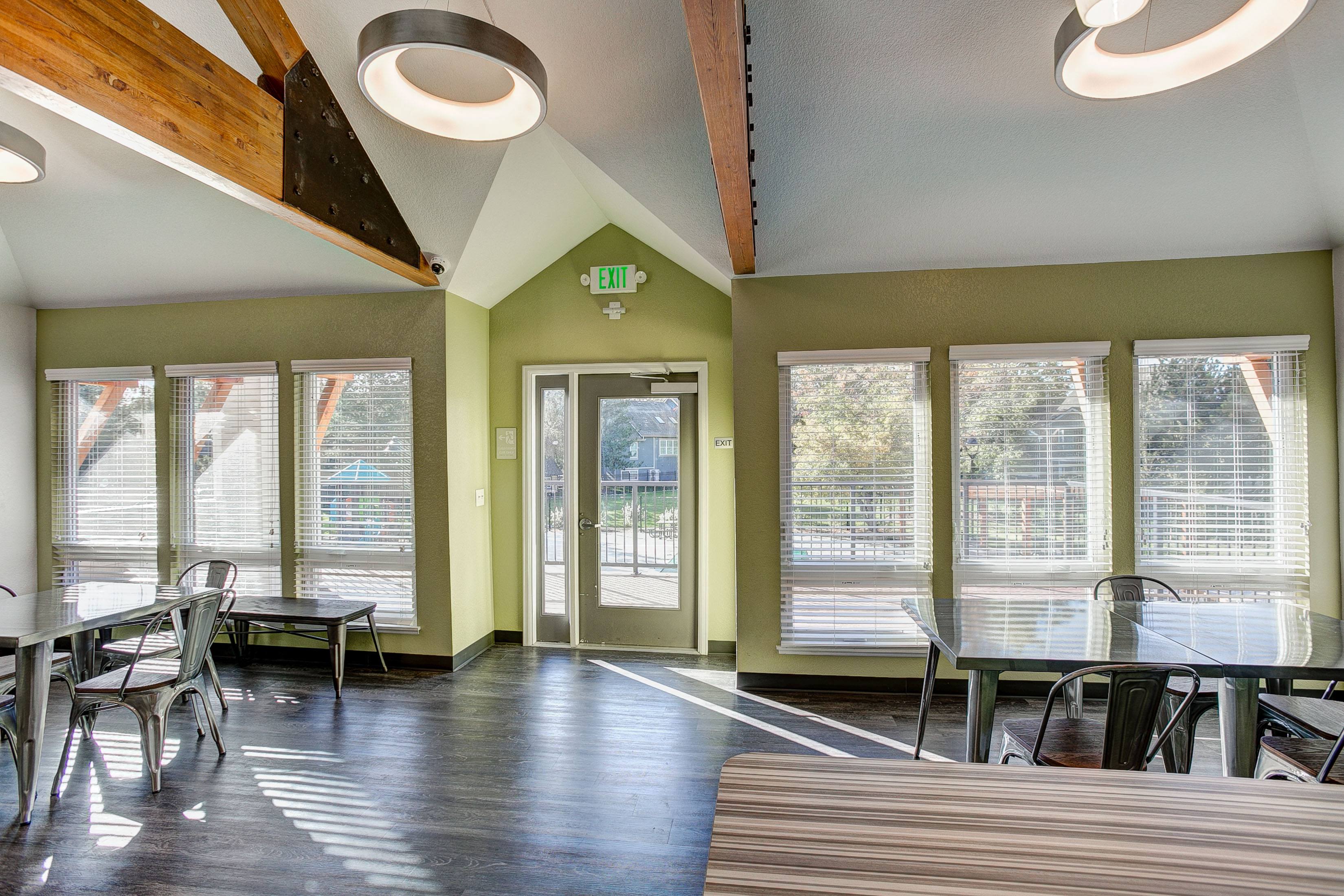 A room with a table and chairs and a green exit sign on the wall.
