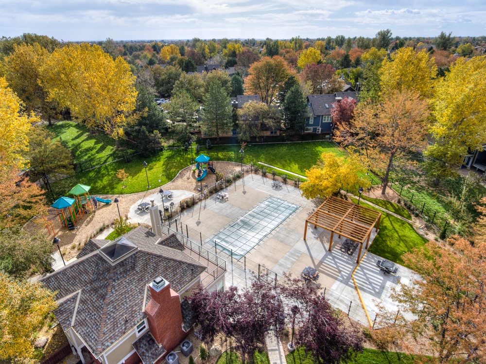 A playground with a slide and a swing set surrounded by trees.