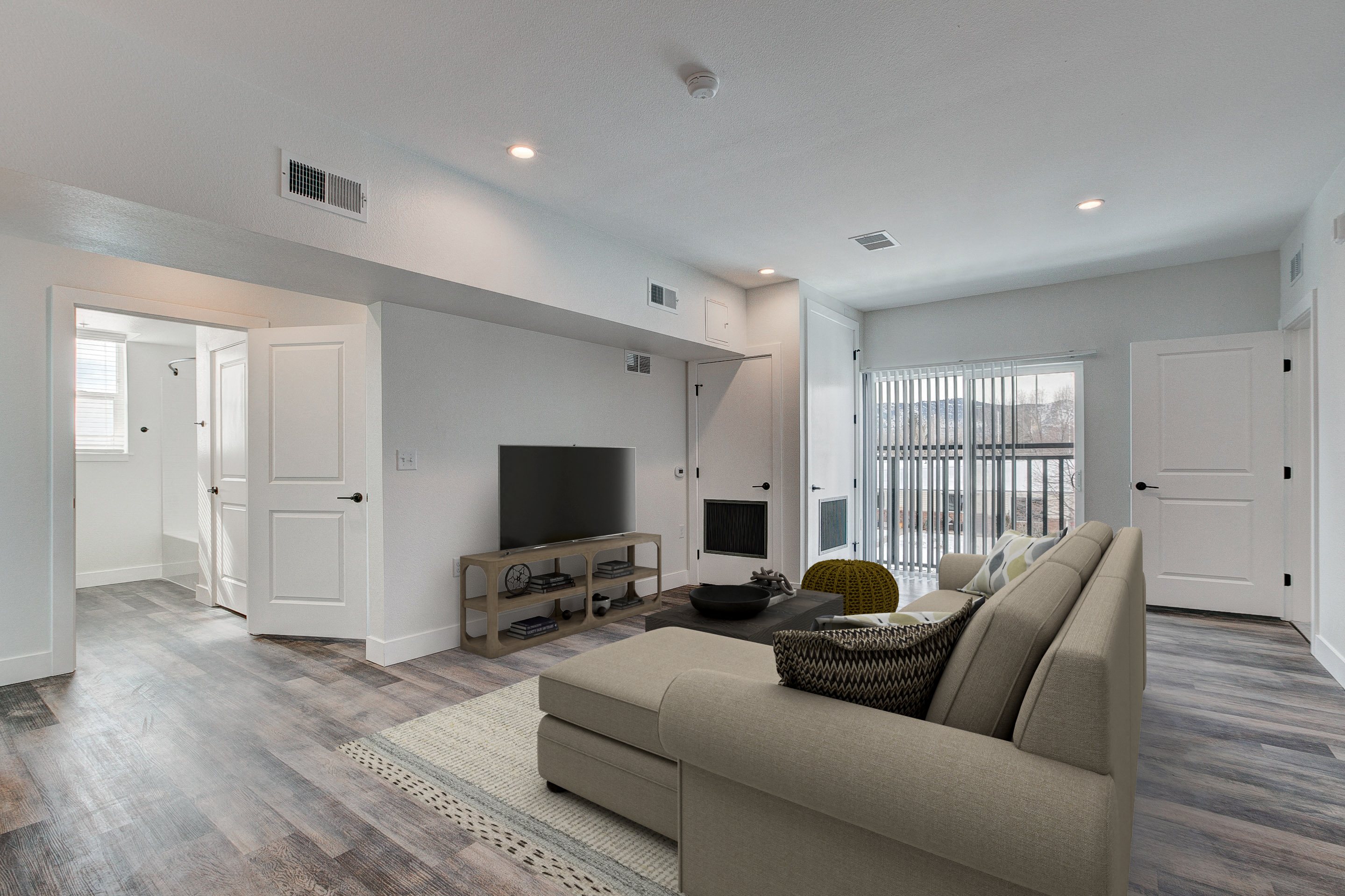 A living room with a couch, a television, and a window with blinds.