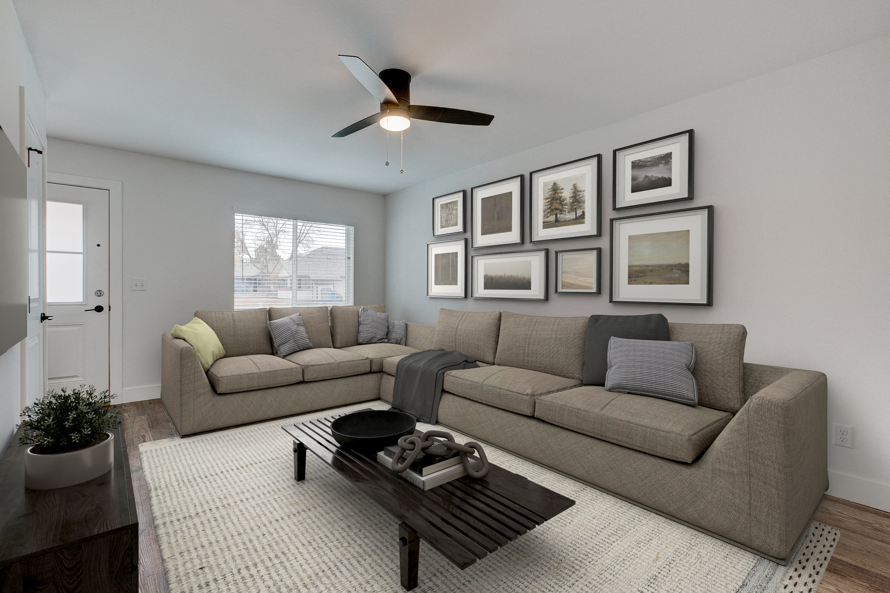 A living room with a grey couch, a coffee table, and a ceiling fan.