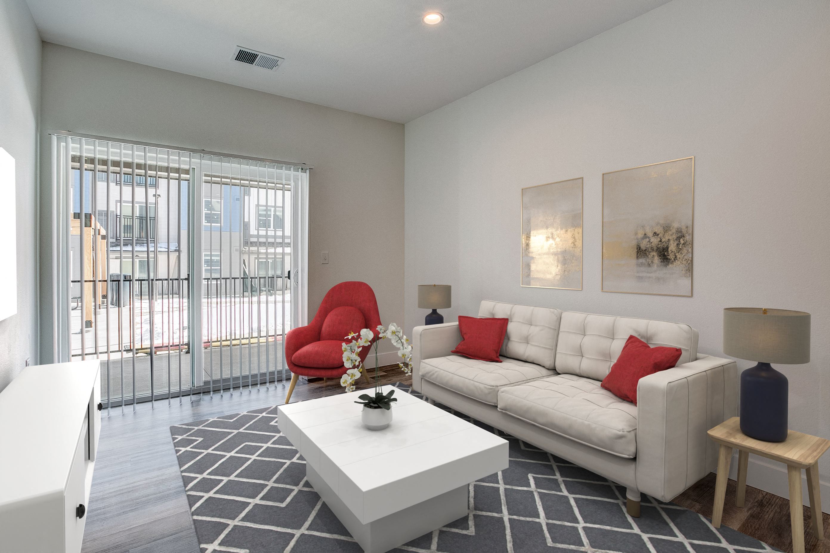 A white couch with red pillows sits in a living room with a red chair and a coffee table.