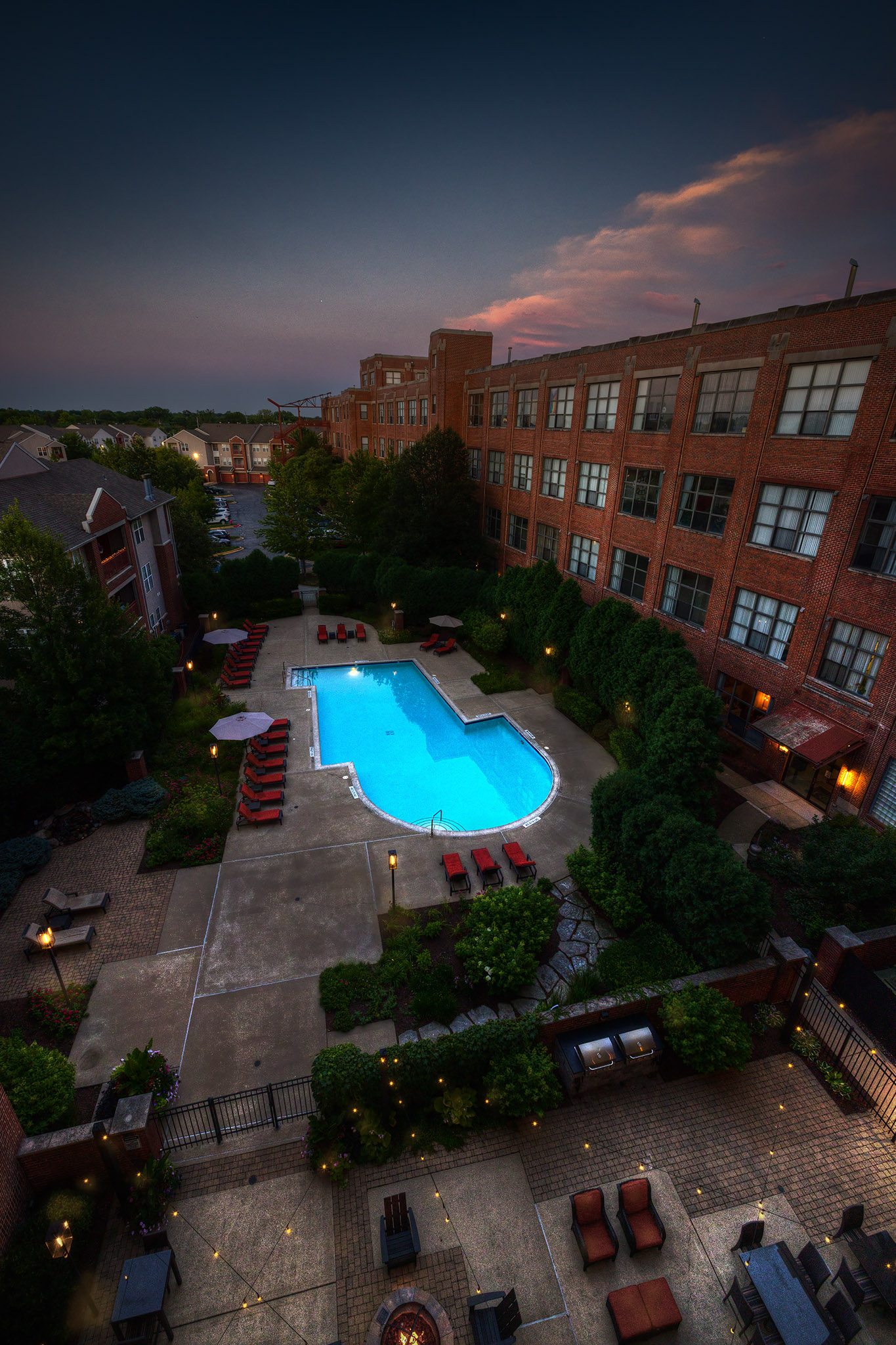 A pool surrounded by a patio with chairs and umbrellas.