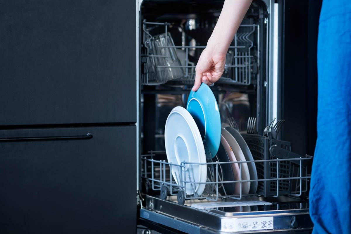 A person is taking a dish out from a dishwasher in an apartment