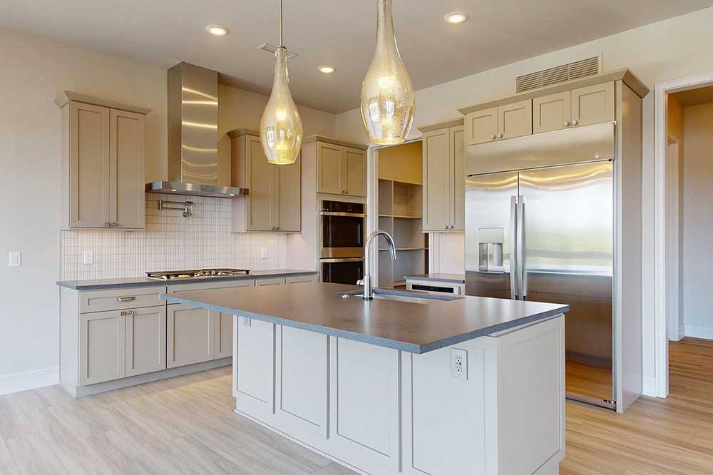 Penthouse finishes penthouse kitchen with light tan wood flooring, tan counters, premiumm stainless appliances, and creamy walls
