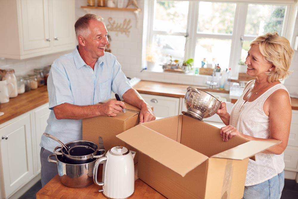 A man and woman packing moving boxes in a kitchen