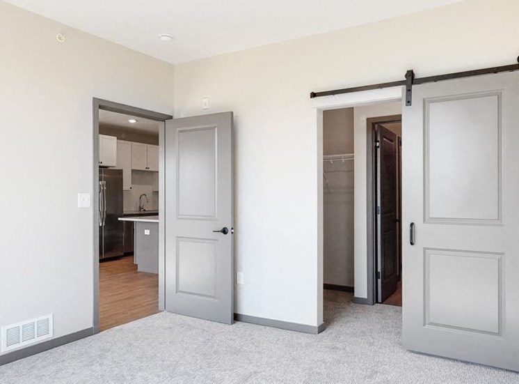 Sliding barn doors leading to closet space and the bathroom from the bedroom in the Bliss floor plan at Haven at Uptown in Lincoln, NE