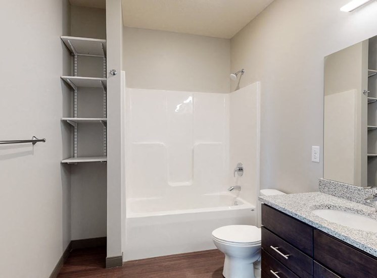 Bathroom with dual sink counter tops, a bathtub, and shelves for additional storage at Haven at Uptown in Lincoln, NE
