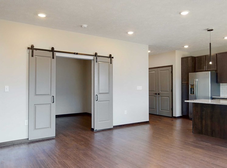 Living space with sliding barn doors leading to an office space in the Melody floor plan at Haven at Uptown in Lincoln, NE