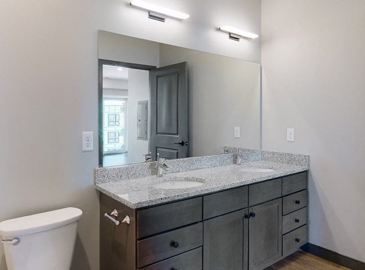Dual sinks and light granite counter tops, as well is slate grey cabinetry for extra storage in the bathroom at Haven at Uptown in Linooln, NE