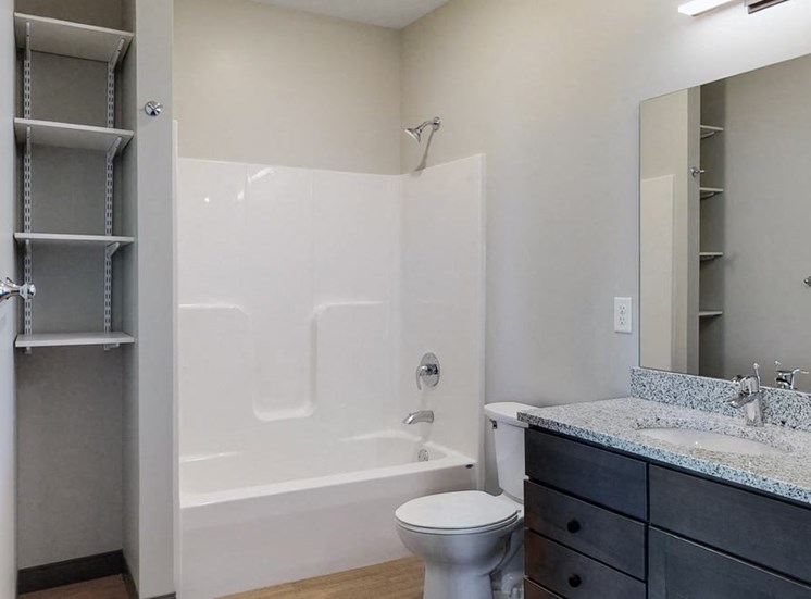 Bathroom with dual sink counter tops, a bathtub, and shelves for additional storage at Haven at Uptown in Lincoln, NE