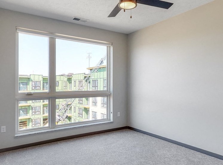 Bedroom with large window and ceiling fan in the Melody floor plan at Haven at Uptown in Lincoln, NE
