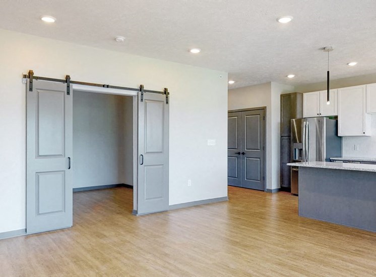 View of sliding barn doors leading into the office area from the living-dining space in the Melody floor plan at Haven at Uptown in Lincoln, NE
