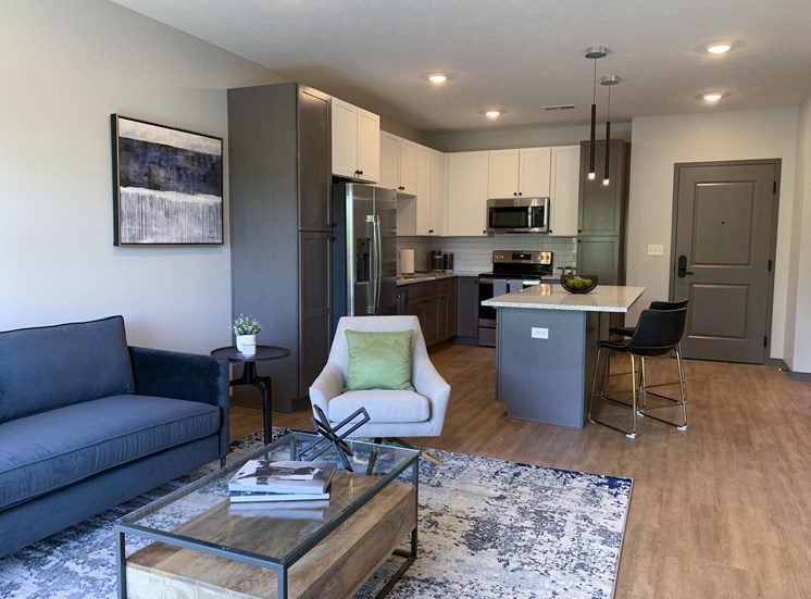 Furnished open concept living room looking into large kitchen in Bliss floor plan at Haven at Uptown in Lincoln.
