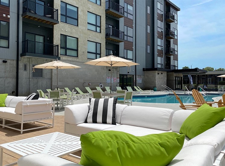 White outdoor sofa with decorative pillows near the pool outside Haven at Uptown.