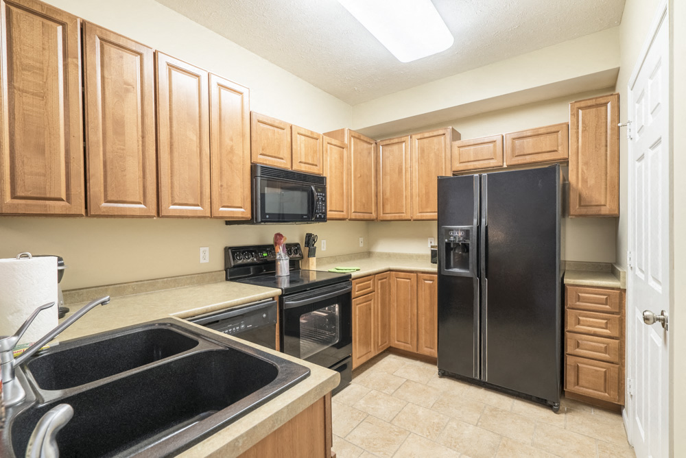 Traditional style U-shaped kitchen with black appliances and warm brown cabinets