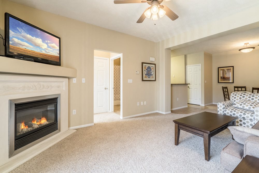 Interiors-Living room with fireplace and ceiling fan at Ridge Pointe Villas