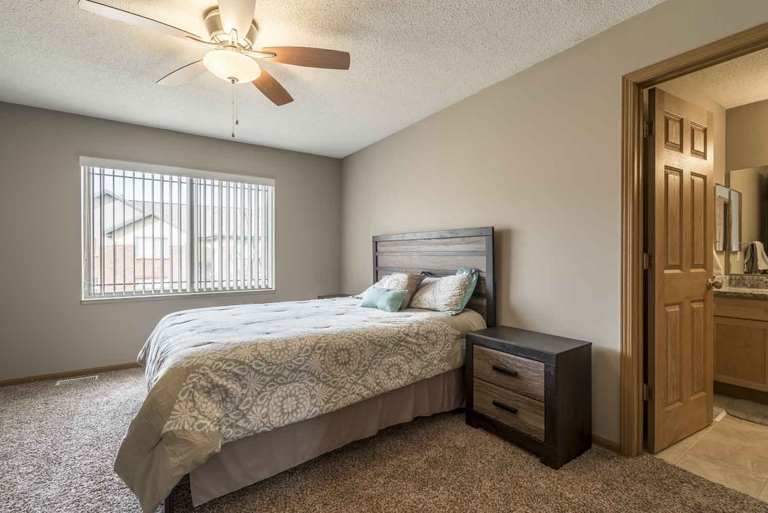 Master bedroom with attached bathroom and ceiling fan at Southwind Villas in southwest Omaha in La Vista, NE, 68128