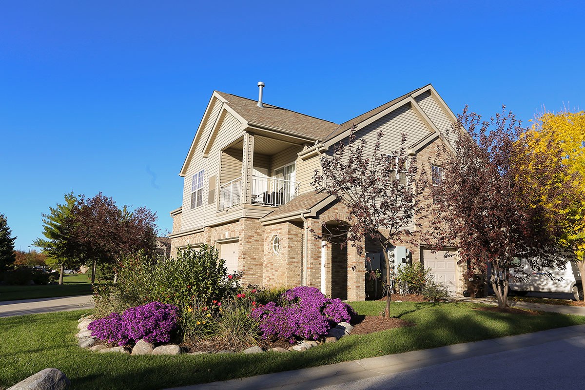 the front of a villa building with a yard with purple flowers