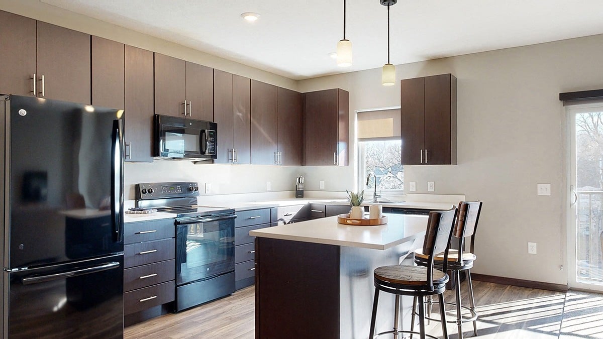a large kitchen with stainless steel appliances and dark brown wooden cabinets