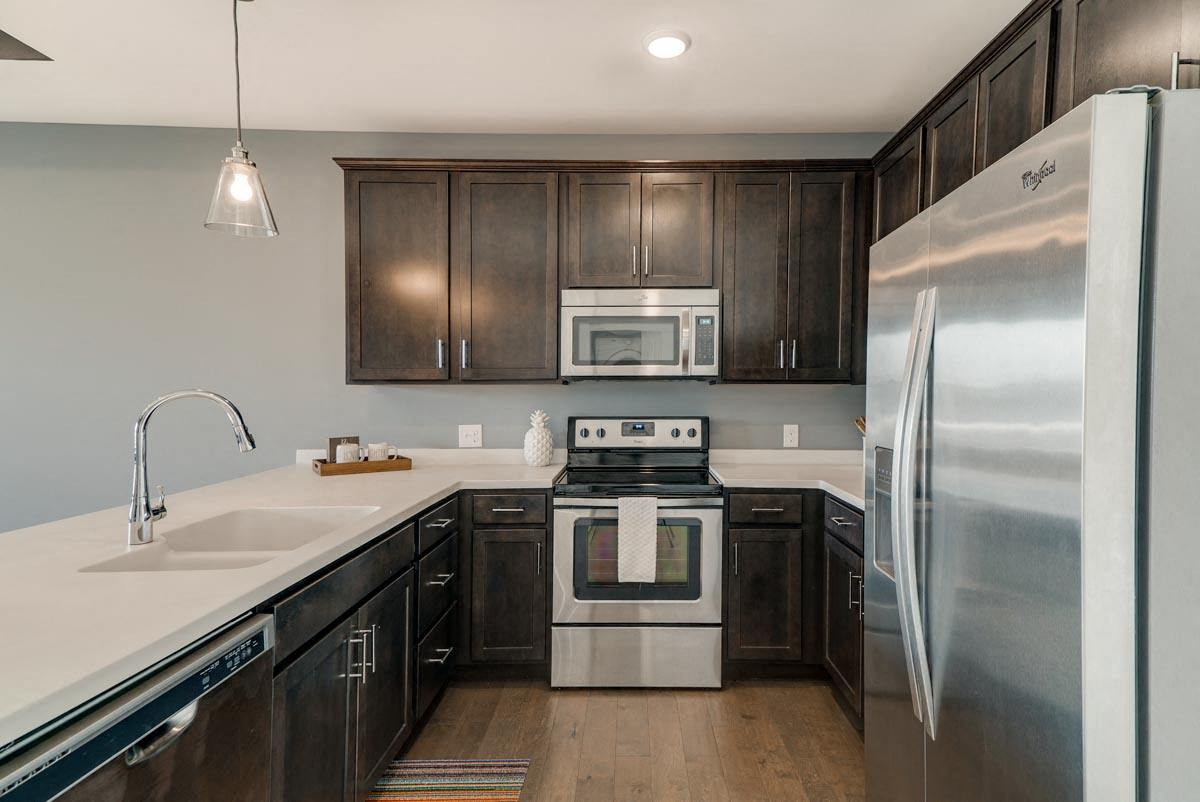 Brown cabinets, white trim A modern kitchen with dark wood cabinets and stainless steel appliances.