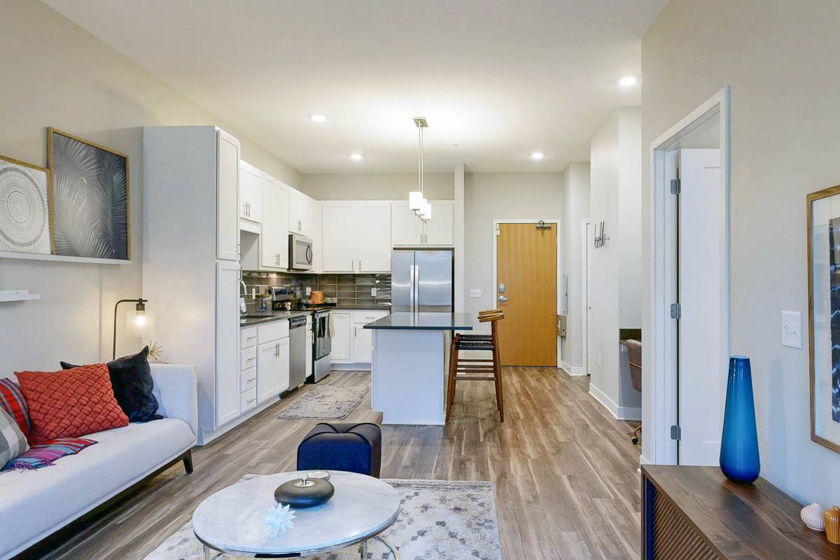 Apartment kitchen and living room in an apartment with white cabinets and an island with seating