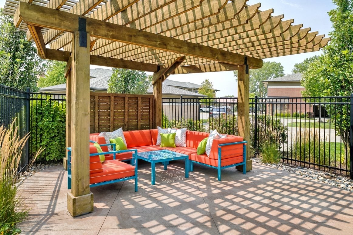 Wood pergola area with bright orange and turquoise lounge furniture positioned under it