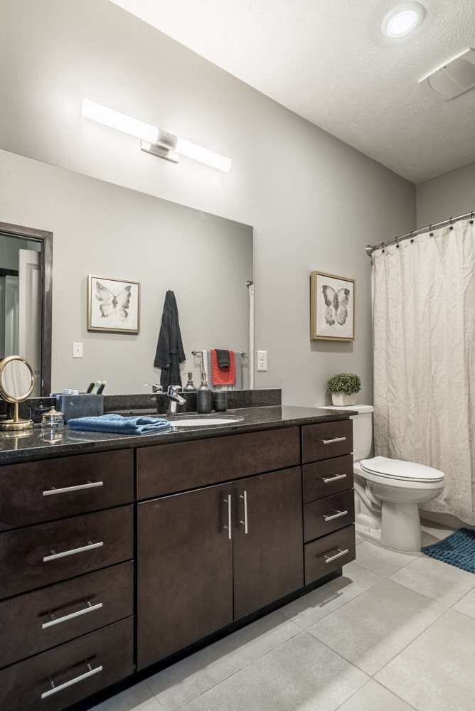Bathroom with dark cabinets and light tile floors at The Villas at Mahoney Park