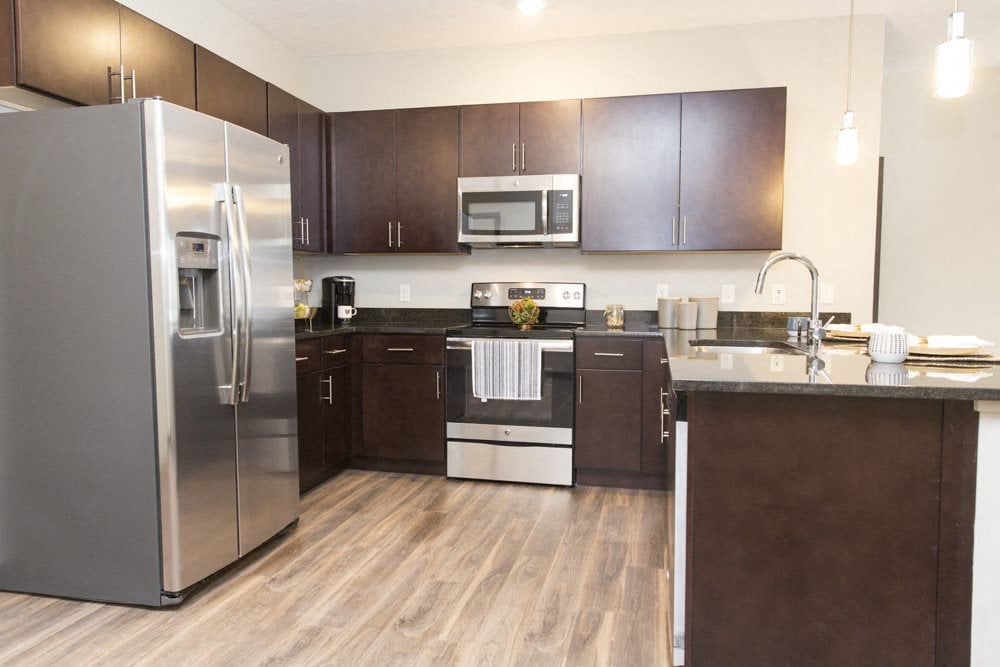 Traditional design kitchen with dark cabinetry and granite countertops with stainless steel appliances at Villas at Mahoney Park apartments