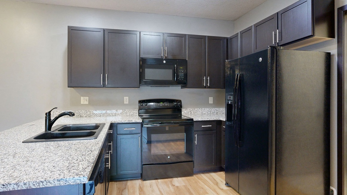 apartment kitchen with dark cabinets and granite countertops