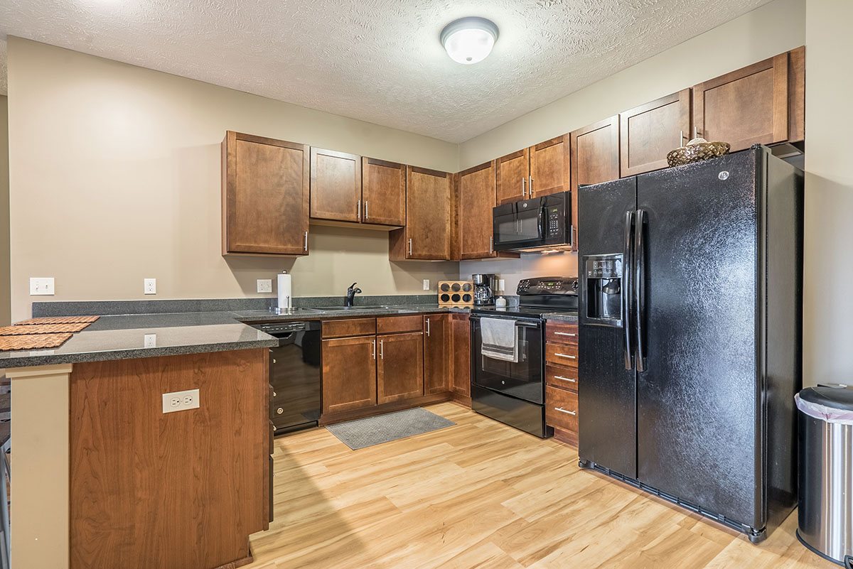 a kitchen with cherry cabinets, a stove, refrigerator and sink