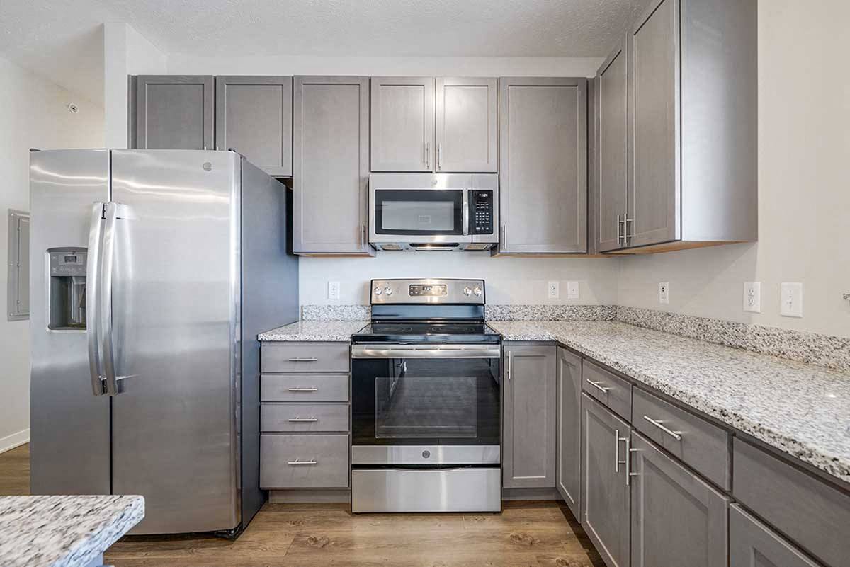 U-shaped kitchen with warm gray cabinets, stainless appliances, and white counters