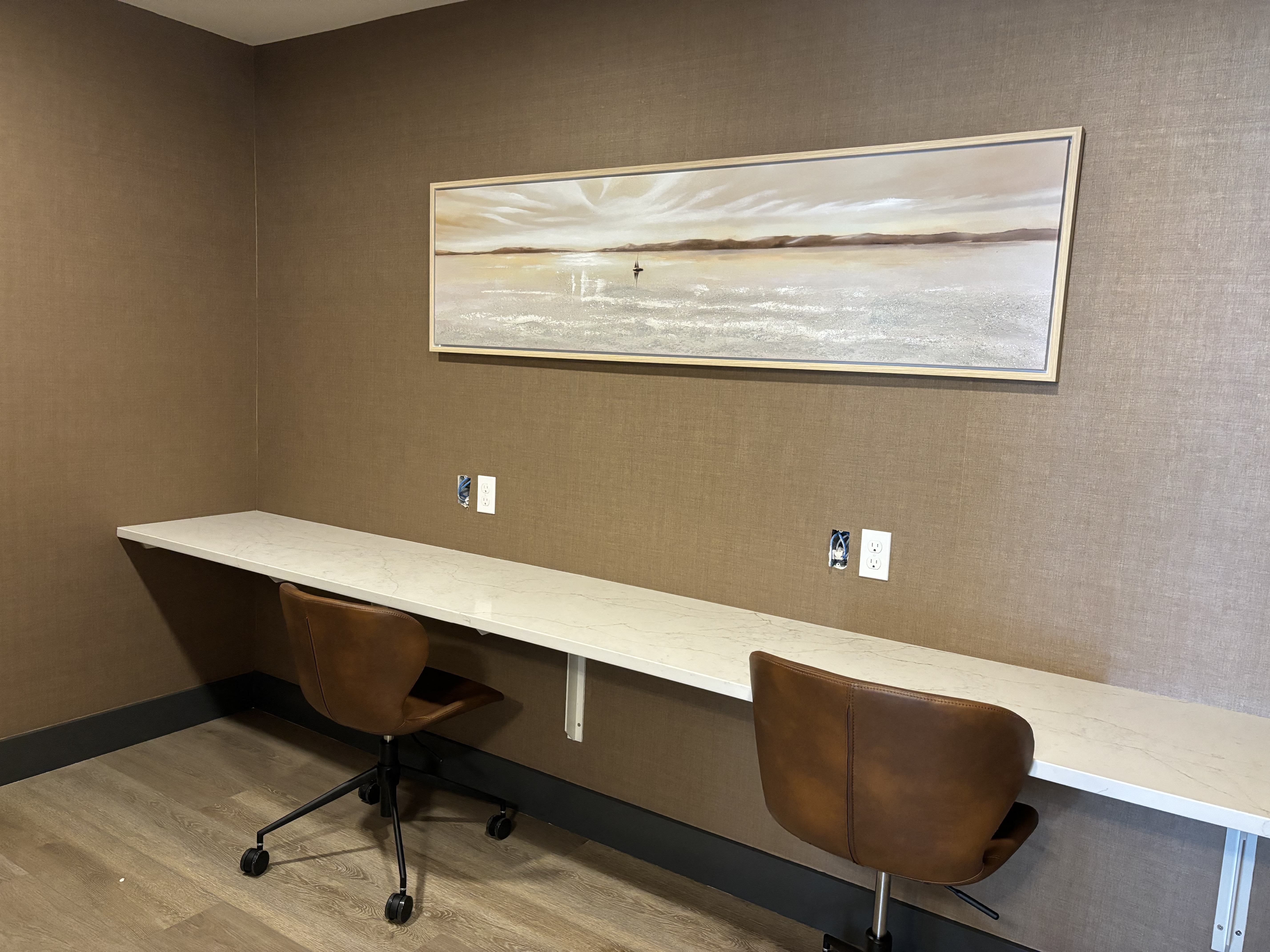 a conference room with two desks and two chairs and a painting on the wall