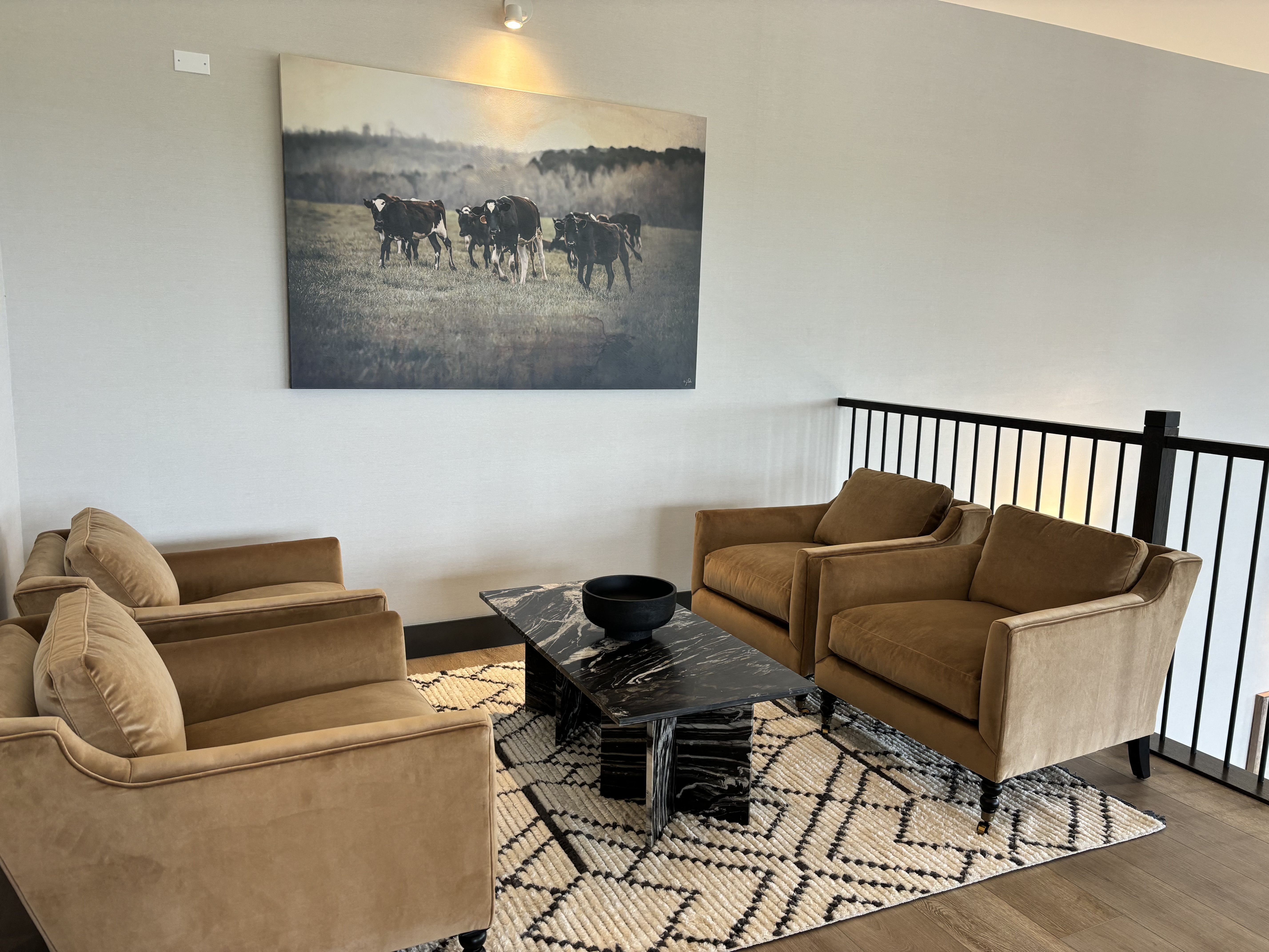 a living room with two brown couches and a painting of cows