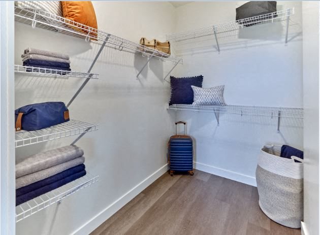 a walk in closet with shelves and a suitcase