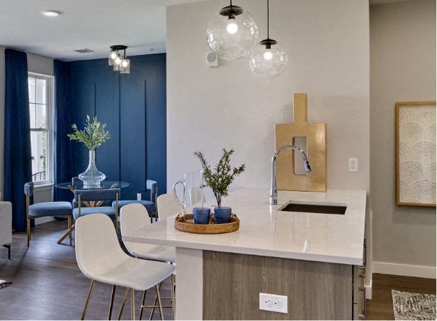 a kitchen with a white counter top next to a dining room