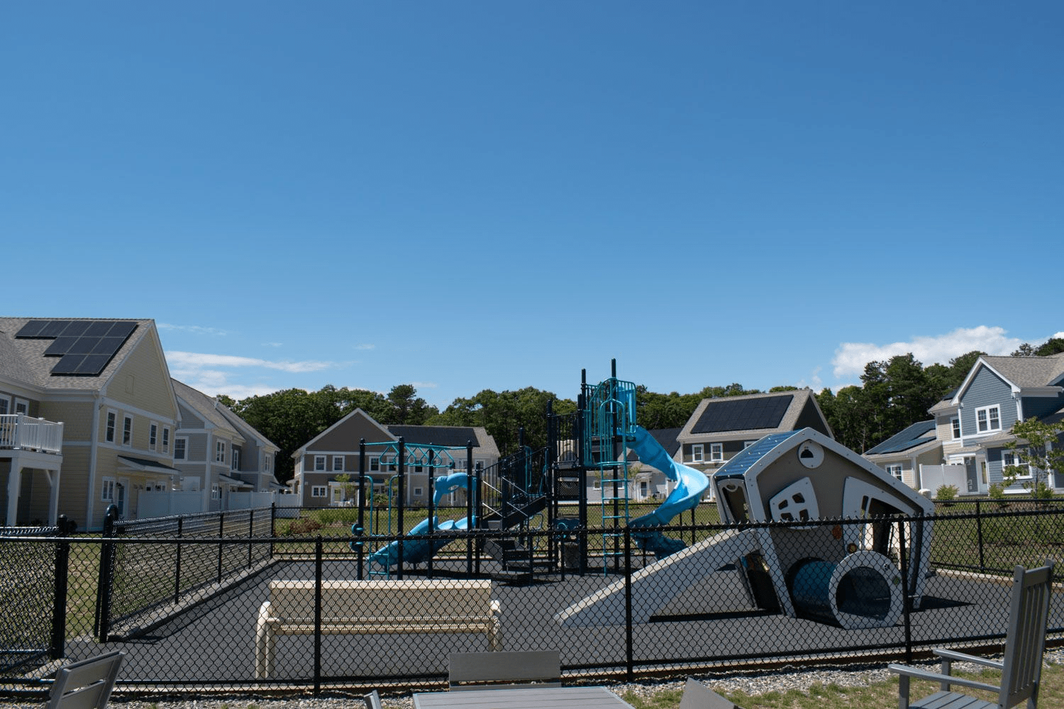 a playground with slides and other equipment in front of a row of houses