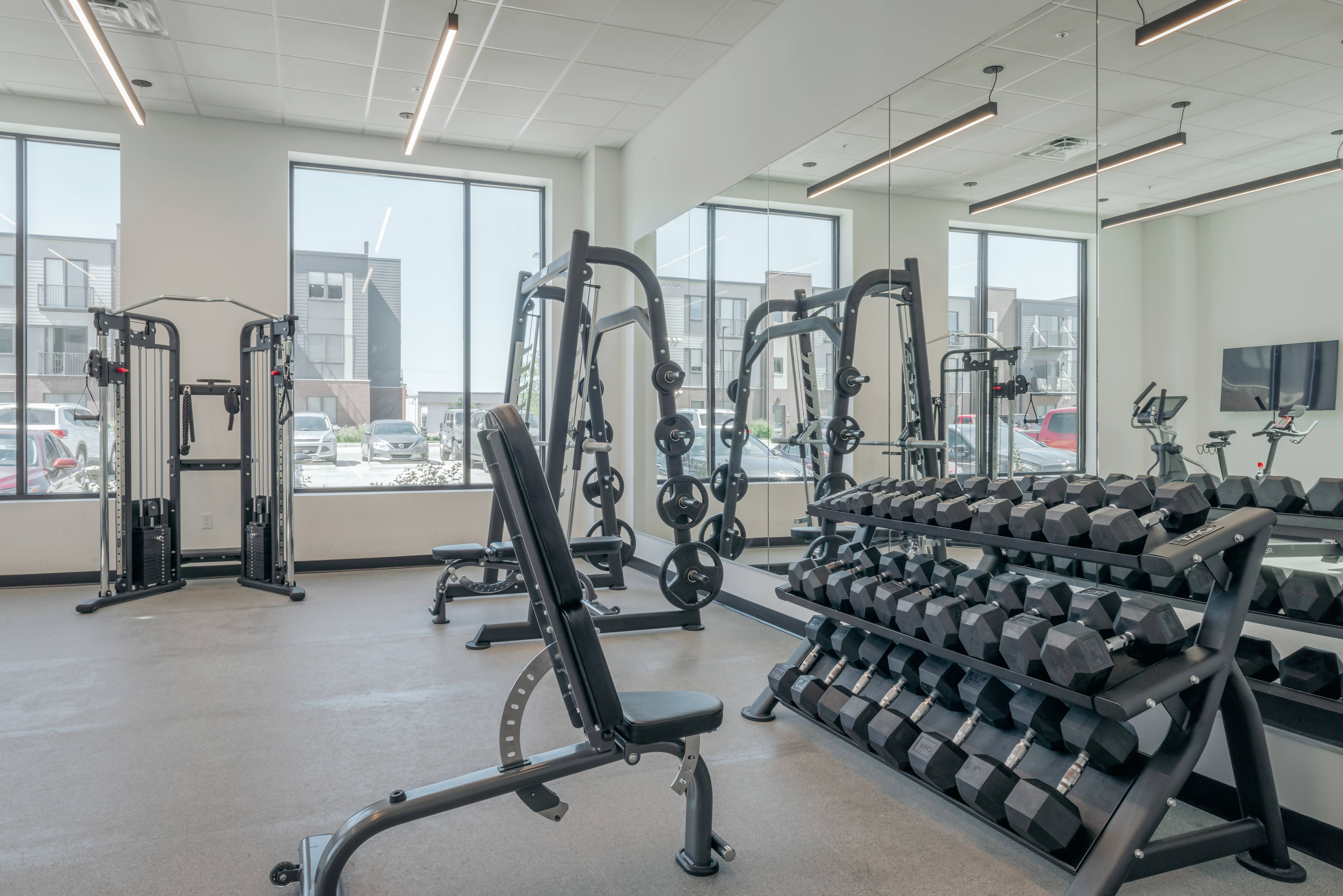 A gym with a variety of equipment including treadmills, weights, and exercise machines.