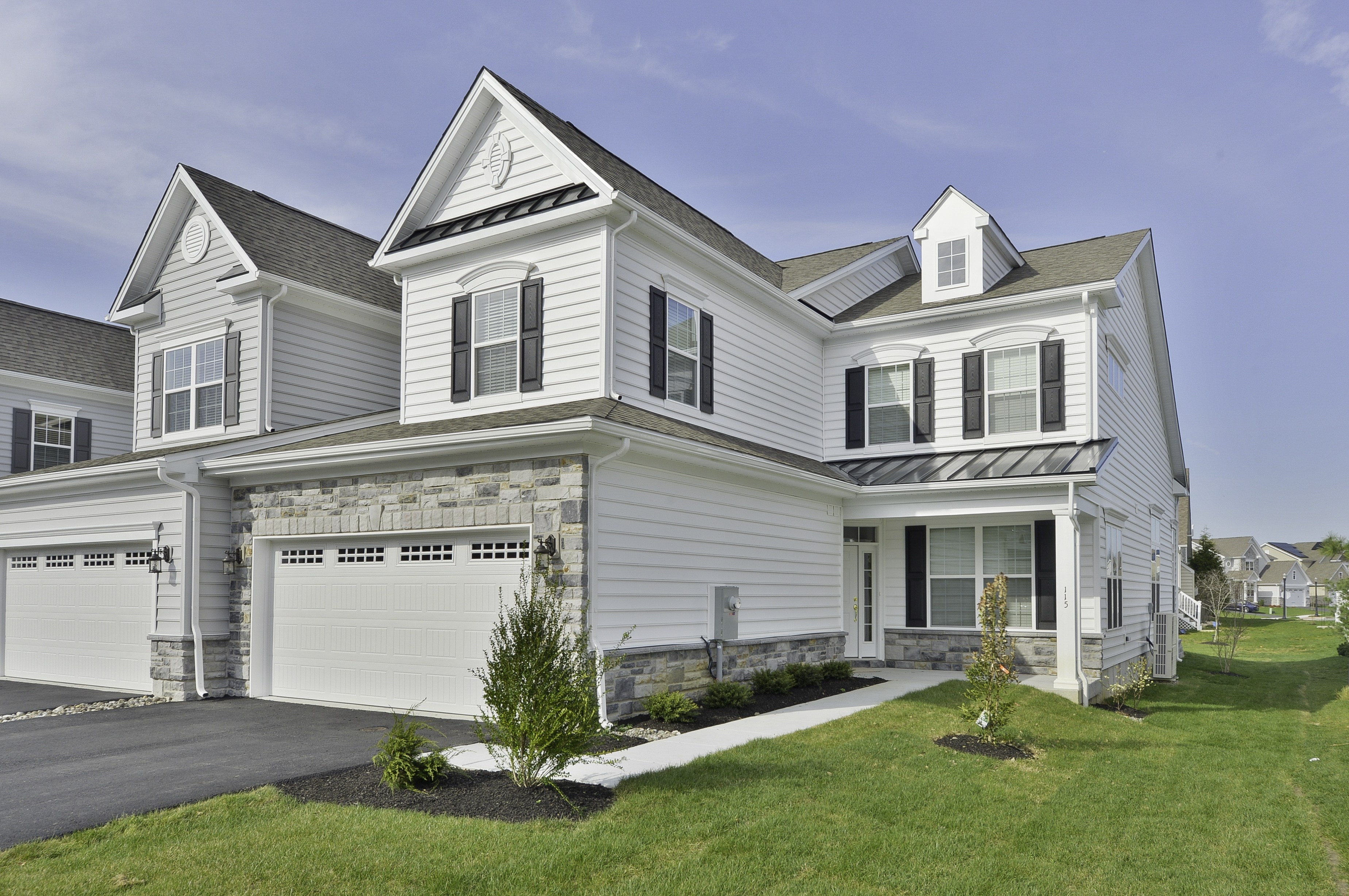 A large, two-story house with a garage on the first floor and a balcony on the second floor.