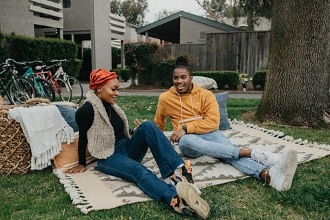 Two Sundance residents sit on the grass talking.