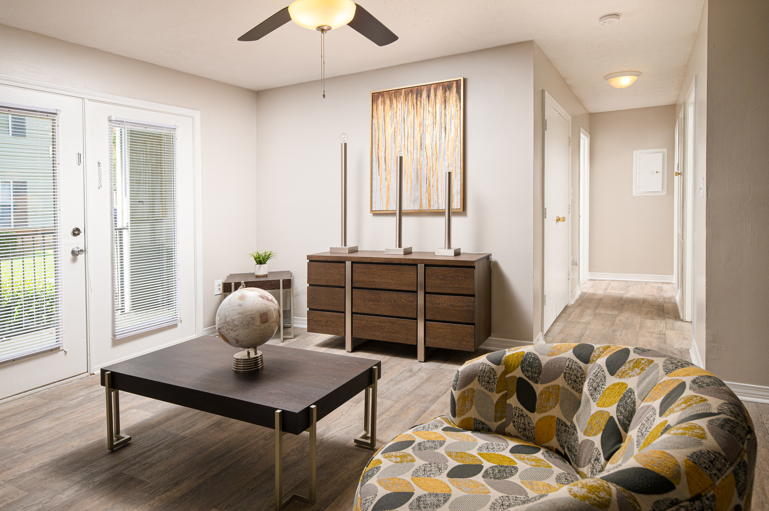 a living room with a ceiling fan and a door leading to a hallway