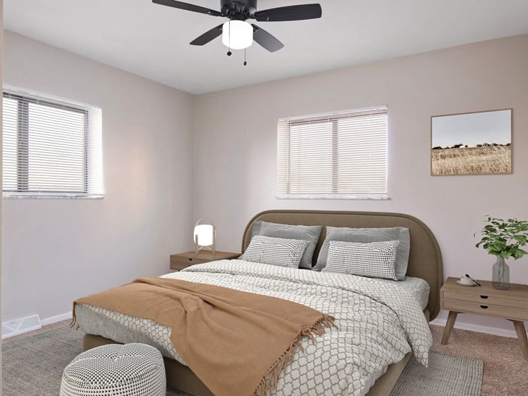 a bedroom with a ceiling fan and two windows